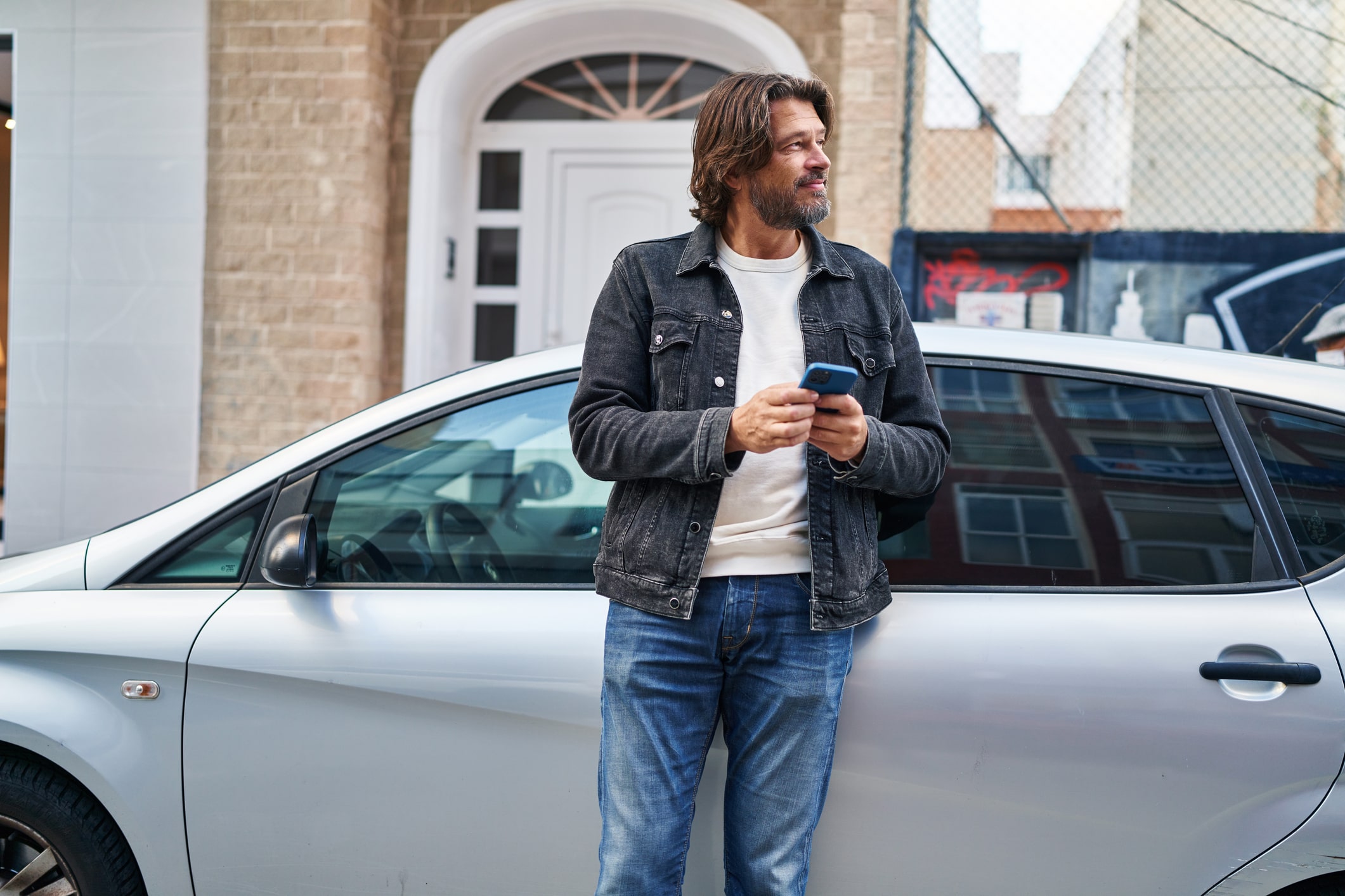 man standing in front of his car on his phone
